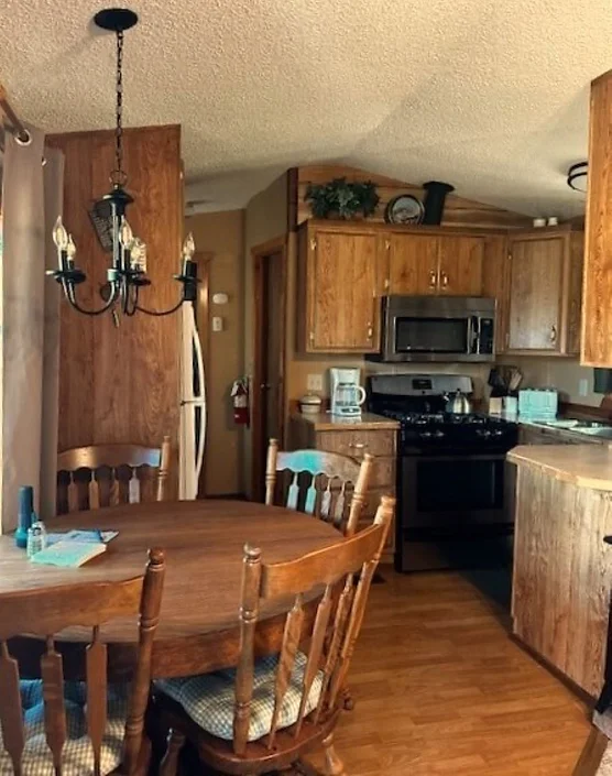 Cozy kitchen with wood cabinets, round dining table, four chairs, and stainless steel appliances.