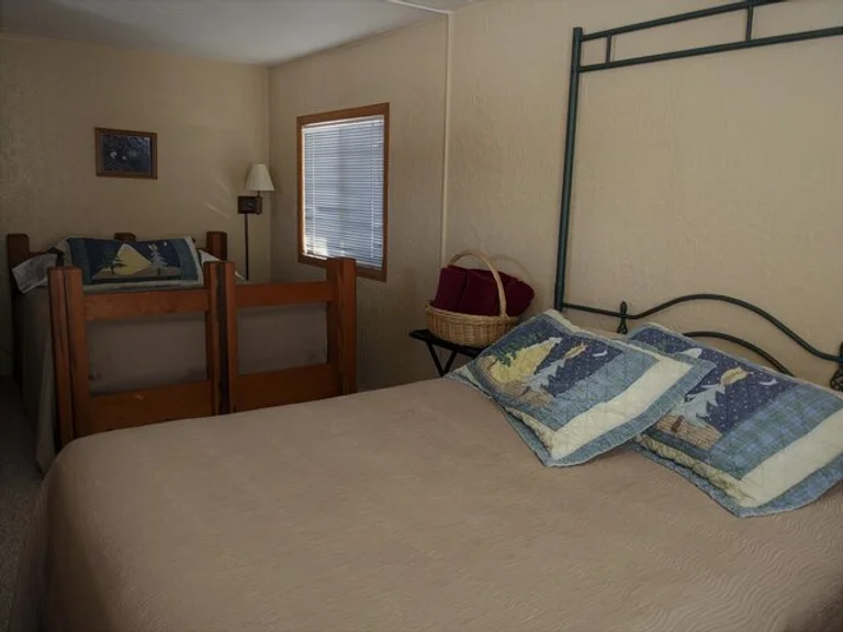 A bedroom with a double bed in the foreground and two twin beds with guardrails in the background.